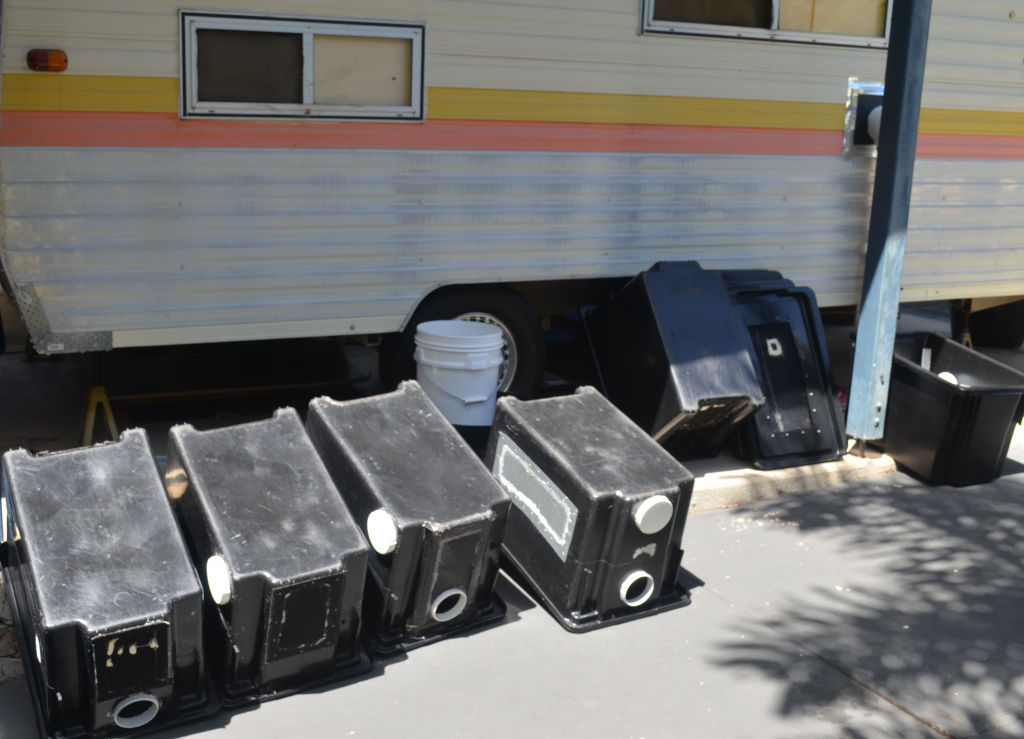 Photo of black cricket containers drying against the outside of a caravan insect farm.