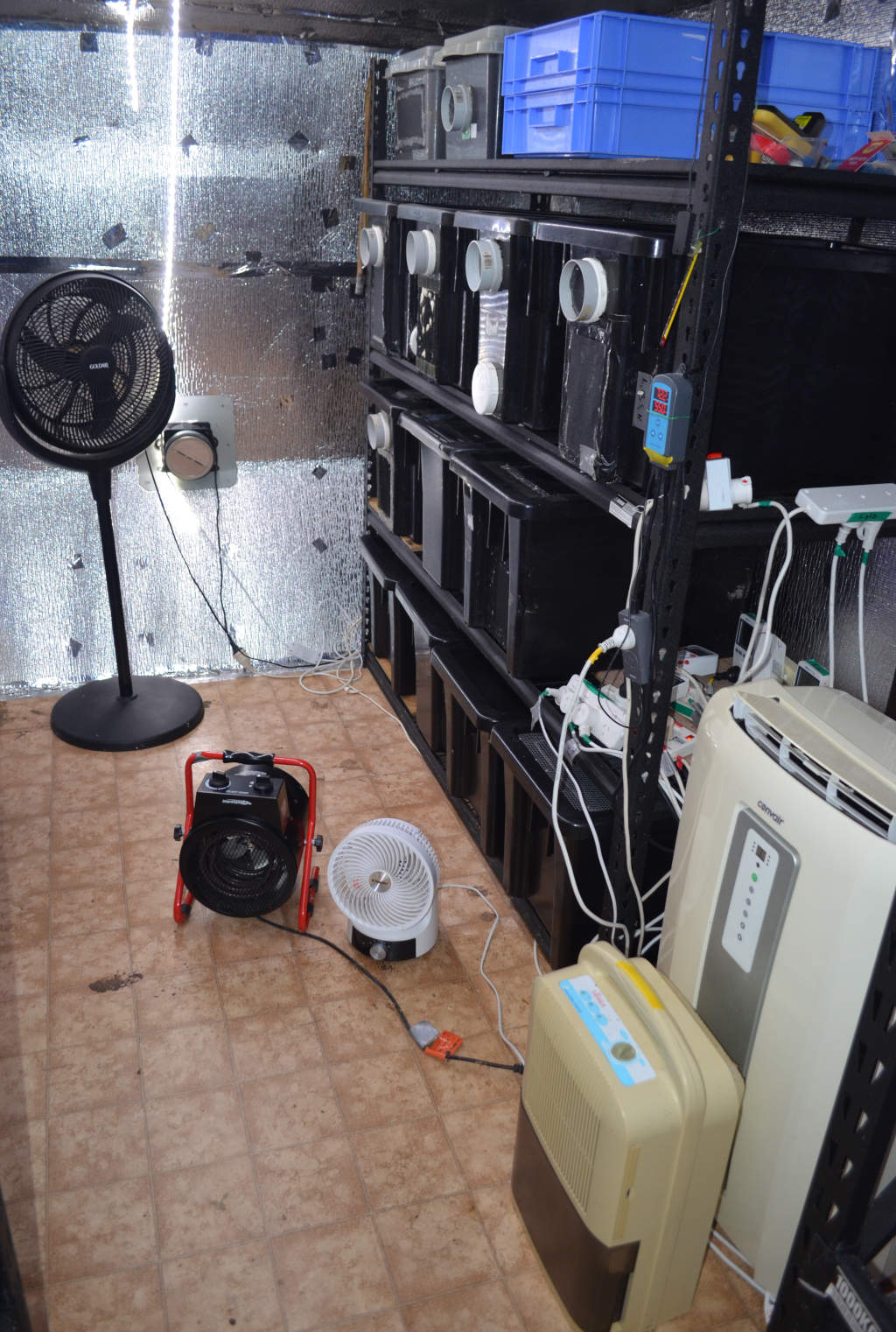 Photo of climate control equipment for a cricket farm. Includes black pedestal fan, black radiant heater, white 360 degree fan, cream air conditioner and dehumidifier.